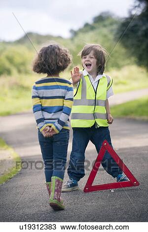 Stock Image - Boy playing traffic worker on rural road. Fotosearch