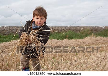 Boy playing with straw in field View Large Photo Image Stock Image - Boy playing with straw in field. Fotosearch