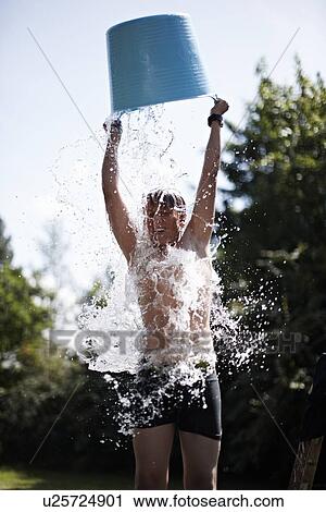 Stock Image - Boy pouring bucket of water on himself. Fotosearch