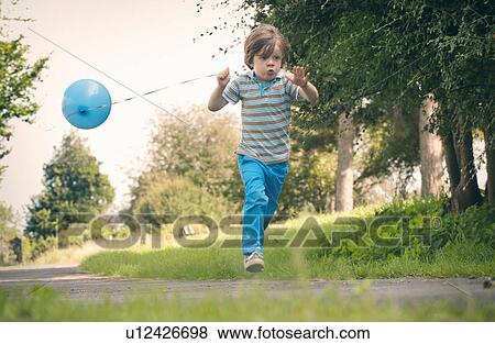 Stock Photo - Boy running with balloon outdoors. Fotosearch
