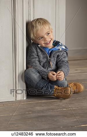 Boy sitting on wooden floor View Large Photo Image Stock Photograph - Boy sitting on wooden floor. Fotosearch
