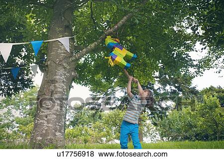 Boy swinging at pinata at party View Large Photo Image Stock Photo - Boy swinging at pinata at party. Fotosearch