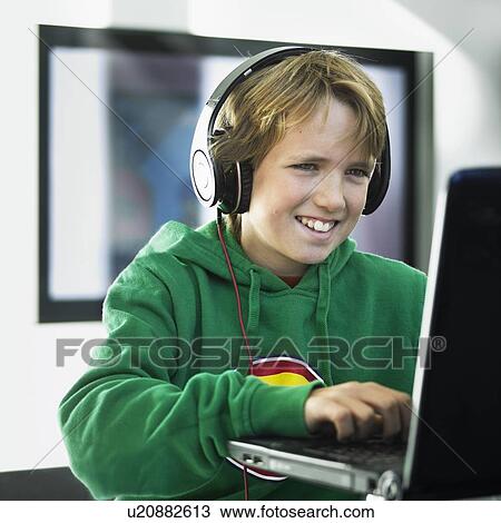 Boy wearing headphones on laptop View Large Photo Image Stock Image - Boy wearing headphones on laptop. Fotosearch