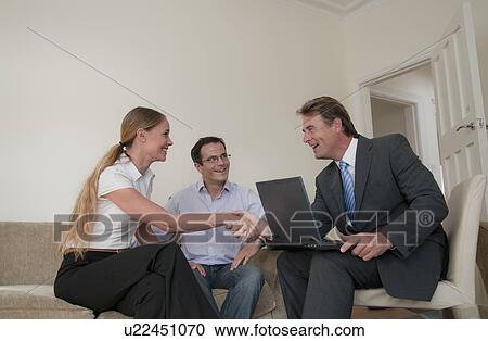 Stock Image - Business people talking in living room. Fotosearch
