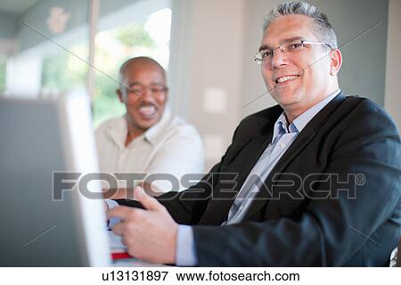 Businessman smiling in meeting View Large Photo Image Stock Photo - Businessman smiling in meeting. Fotosearch