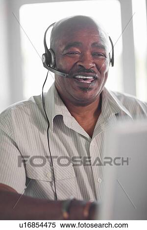 Businessman wearing headset at desk View Large Photo Image Stock Photography - Businessman wearing headset at desk. Fotosearch
