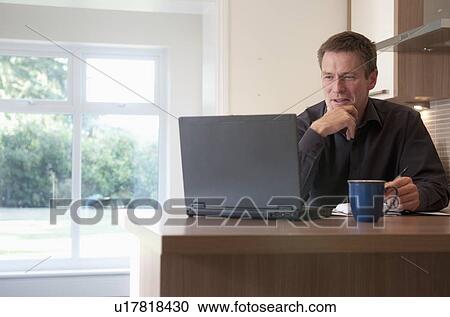 Stock Image - Businessman working on laptop at desk. Fotosearch