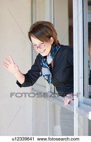 Businesswoman waving out window View Large Photo Image Stock Image - Businesswoman waving out window. Fotosearch