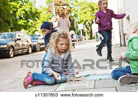 Stock Image - Children drawing on sidewalk with chalk. Fotosearch