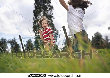 Stock Photo - Children playing in grassy field. Fotosearch