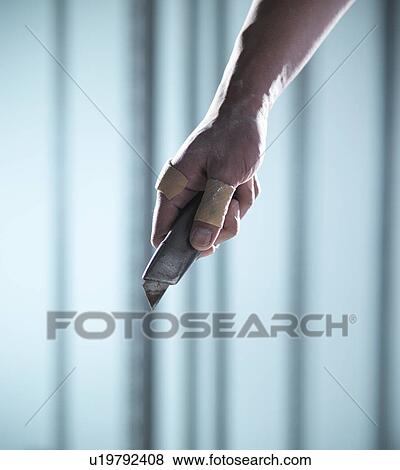 Stock Photo - Close up of hand holding box cutter. Fotosearch