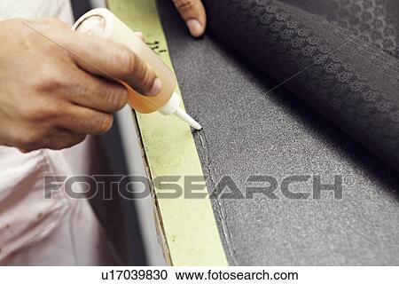Stock Image - Close up of hands gluing fabric. Fotosearch