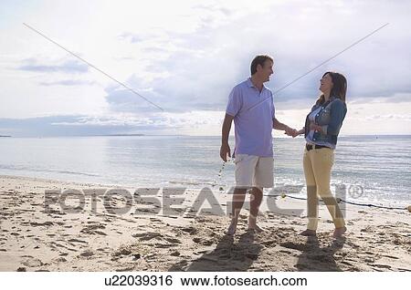 Couple holding hands on beach View Large Photo Image Stock Photograph - Couple holding hands on beach. Fotosearch