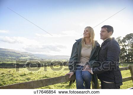 Picture - Couple relaxing on wooden fence. Fotosearch
