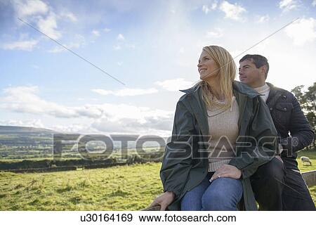 Couple relaxing on wooden fence View Large Photo Image Stock Photo - Couple relaxing on wooden fence. Fotosearch