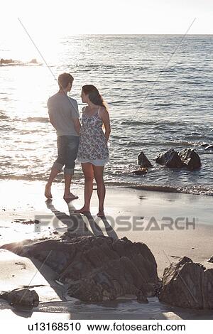 Couple standing together on beach View Large Photo Image Stock Image - Couple standing together on beach. Fotosearch