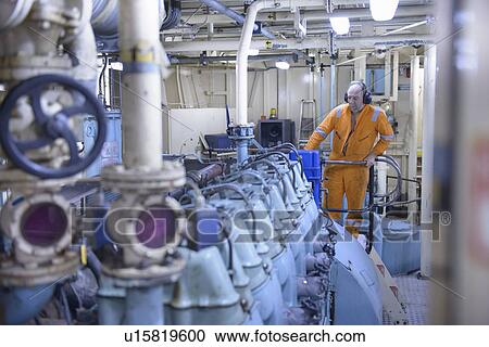 Stock Image - Engineer standing in engine room. Fotosearch