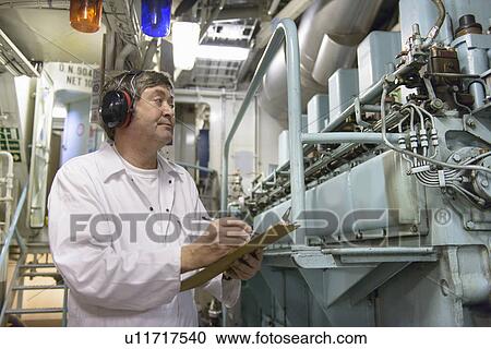 Stock Image - Engineer working in ships engine room. Fotosearch