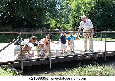 Family examining river on bridge View Large Photo Image Stock Photograph - Family examining river on bridge. Fotosearch