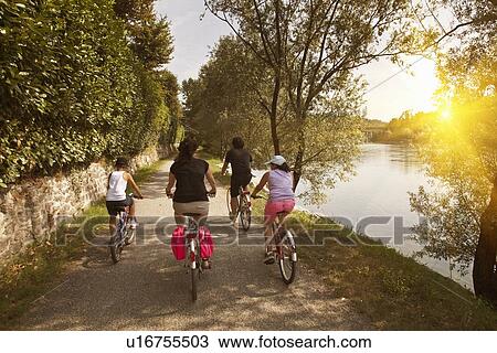 Family riding bicycles by river bank View Large Photo Image Stock Image - Family riding bicycles by river bank. Fotosearch