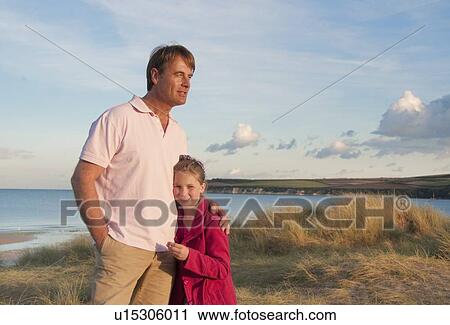 Stock Image - Father and daughter hugging on beach. Fotosearch