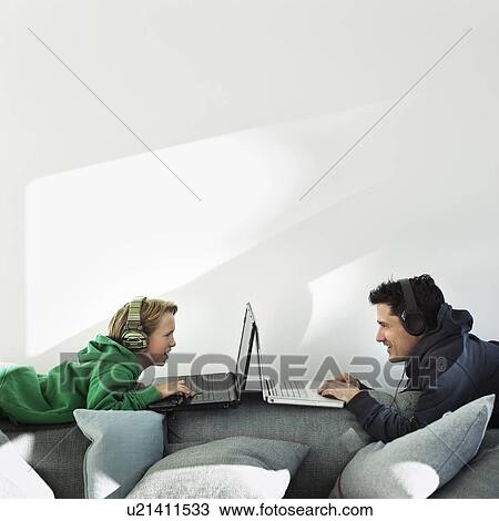 Father and son using laptops on sofa View Large Photo Image Stock Image - Father and son using laptops on sofa. Fotosearch