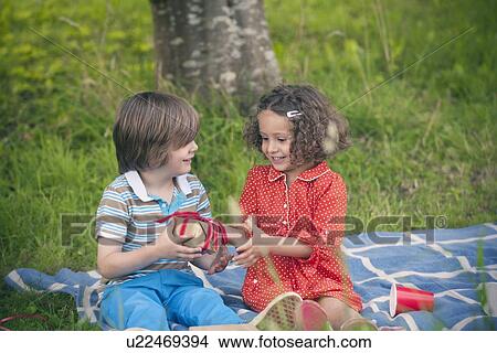 Picture - Girl giving gift at birthday picnic. Fotosearch