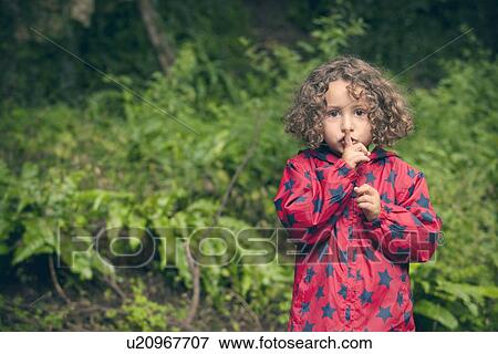 Girl holding finger over lips in forest View Large Photo Image Stock Photo - Girl holding finger over lips in forest. Fotosearch