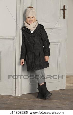 Stock Photography - Girl in winter coat and hat indoors. Fotosearch