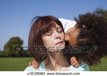 Stock Image - Girl kissing grandmother outdoors. Fotosearch