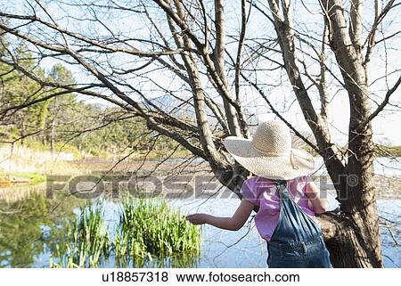 Stock Photo - Girl playing on tree outdoors. Fotosearch