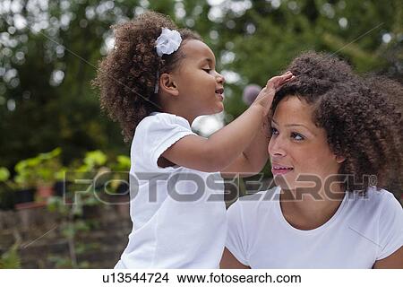 Girl playing with mothers hair outdoors View Large Photo Image Picture - Girl playing with mothers hair outdoors. Fotosearch