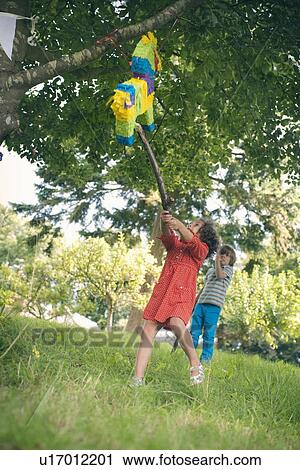 Girl swinging at pinata at party View Large Photo Image Stock Image - Girl swinging at pinata at party. Fotosearch