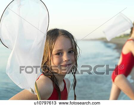 Stock Image - Girls fishing in shallow water. Fotosearch