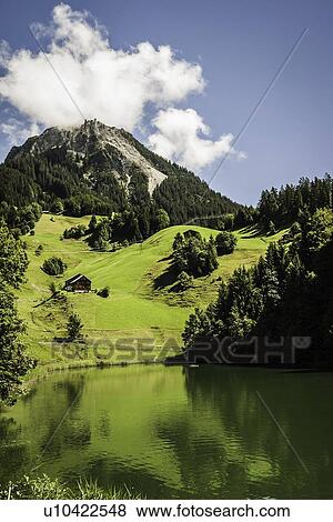 Stock Photo - Grassy hillside by still rural lake. Fotosearch