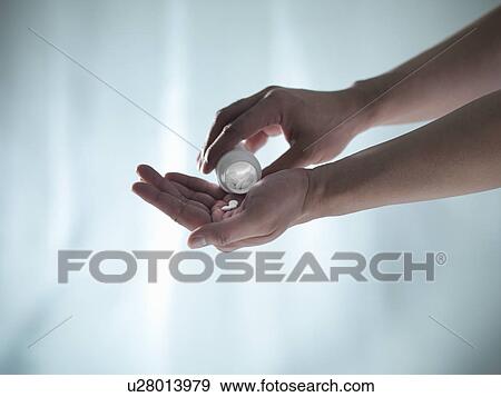 Stock Photo - Hand shaking pills from bottle. Fotosearch