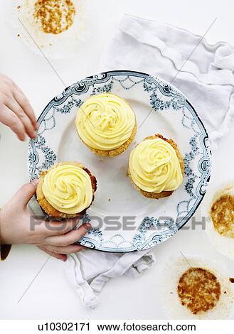 Stock Image - Hands picking cupcakes from plate. Fotosearch