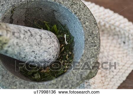 Stock Photograph - Herbs being ground in pestle and mortar. Fotosearch