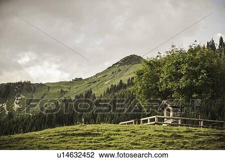 Stock Image - Log cabin on grassy hillside. Fotosearch