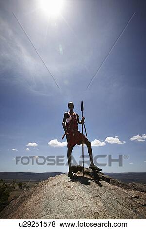 Stock Photo - Maasai man standing on top of rock. Fotosearch