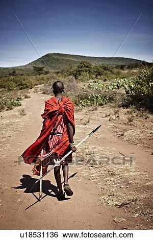 Stock Photograph - Maasai man walking on dirt road. Fotosearch