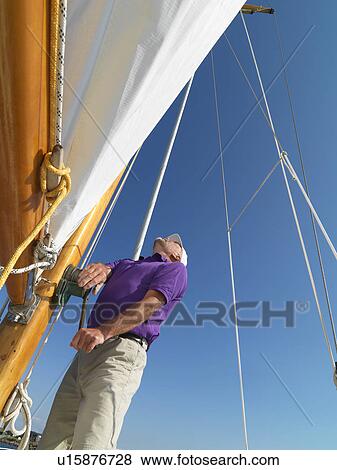 Stock Photo - Man adjusting rigging on sailboat. Fotosearch