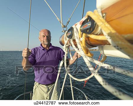 Man adjusting rigging on sailboat View Large Photo Image Stock Photo - Man adjusting rigging on sailboat. Fotosearch