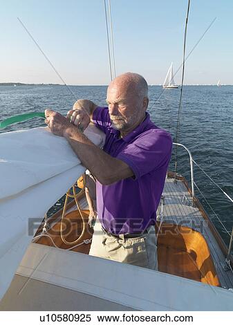 Man adjusting rigging on sailboat View Large Photo Image Stock Photography - Man adjusting rigging on sailboat. Fotosearch