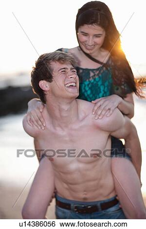 Stock Photograph - Man carrying girlfriend on beach. Fotosearch