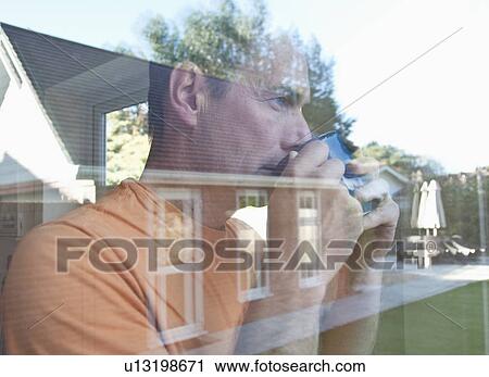 Stock Image - Man having coffee reflected in window. Fotosearch