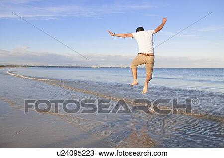 Man jumping for joy in waves on beach View Large Photo Image Stock Image - Man jumping for joy in waves on beach. Fotosearch