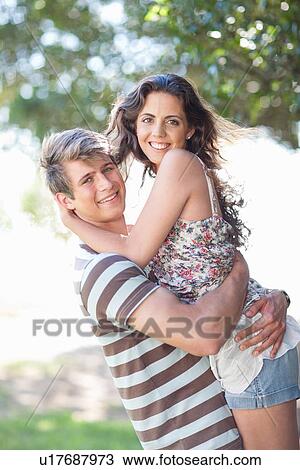 Stock Image - Man lifting girlfriend outdoors. Fotosearch