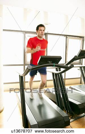 Stock Photo - Man running on treadmill at gym. Fotosearch