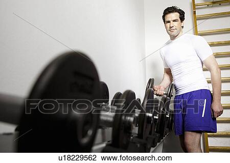 Man using free weights at gym View Large Photo Image Stock Image - Man using free weights at gym. Fotosearch